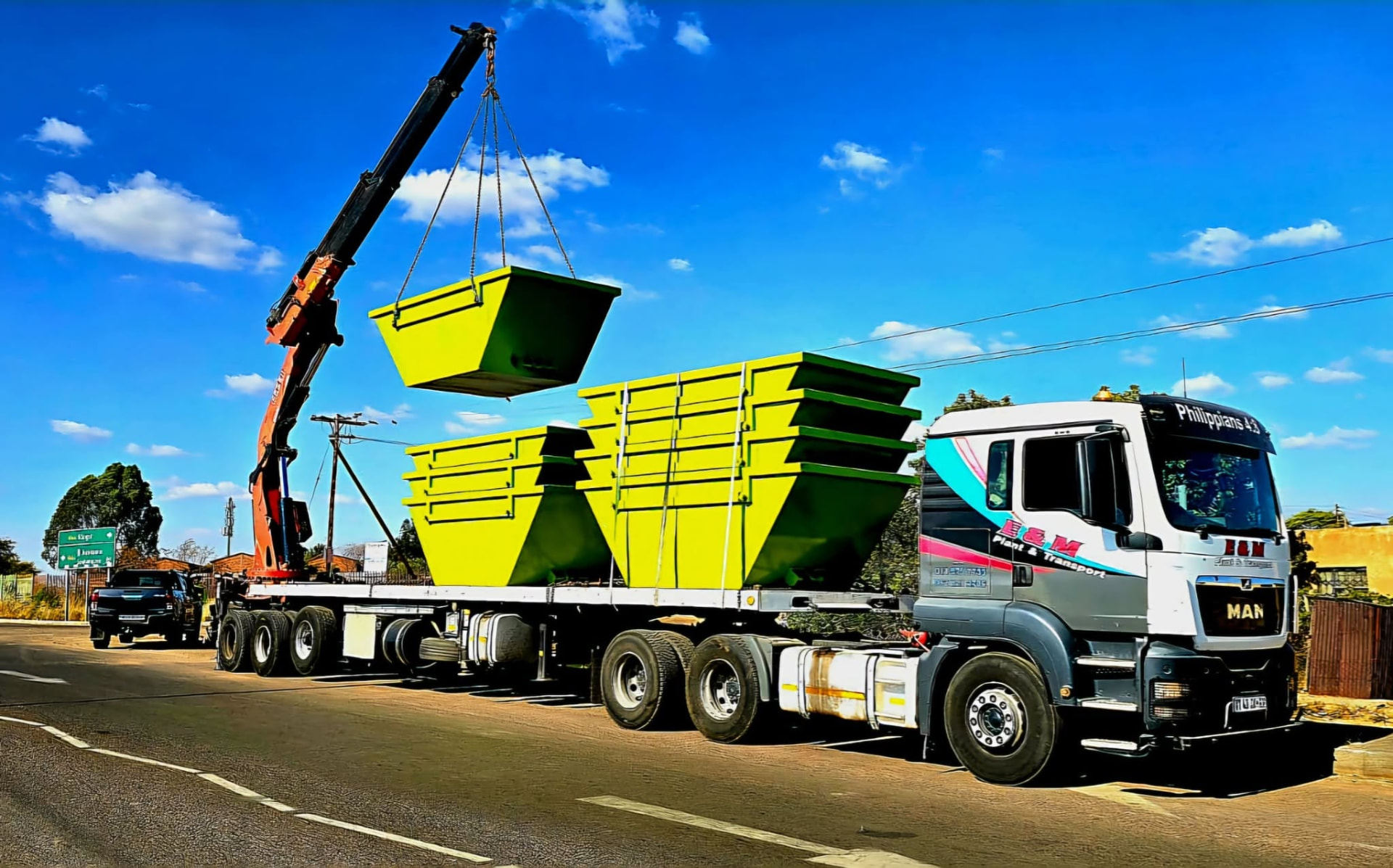 Crane truck lifting yellow skip bins