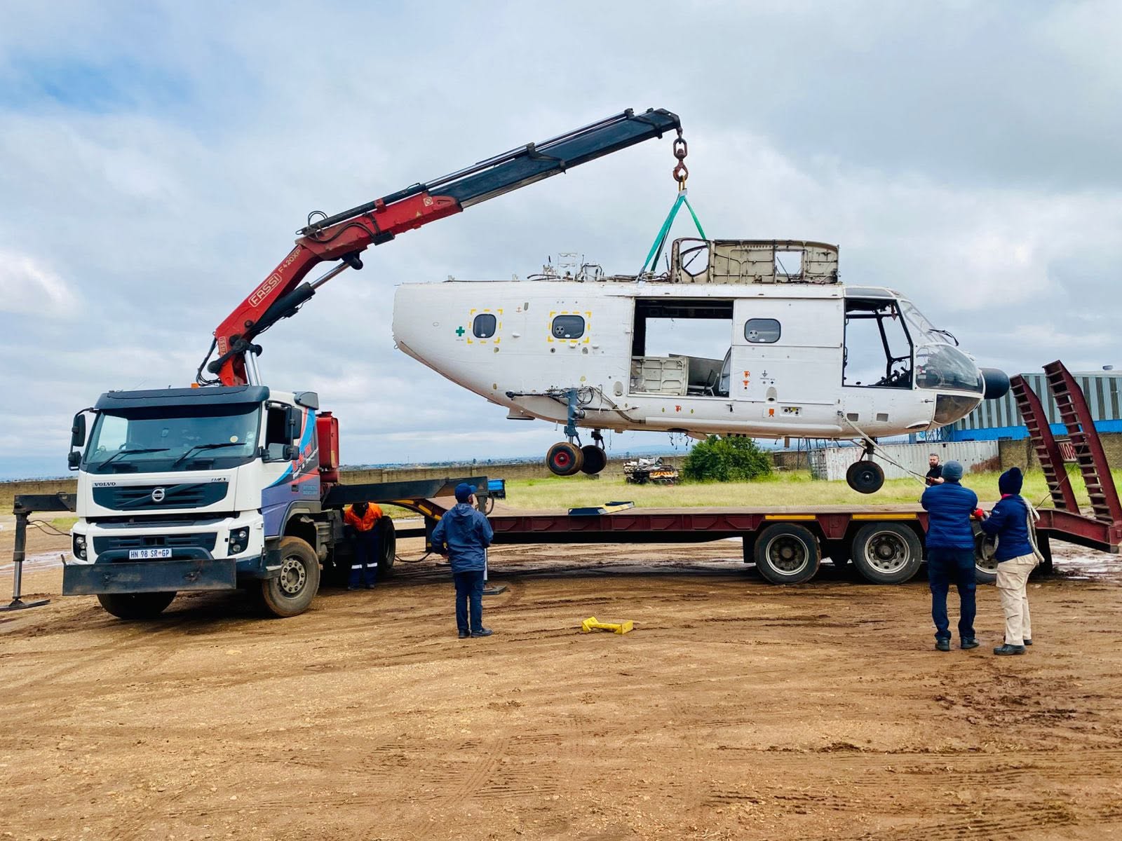 E&M crane truck lifting a helicopter fuselage with rigging crew