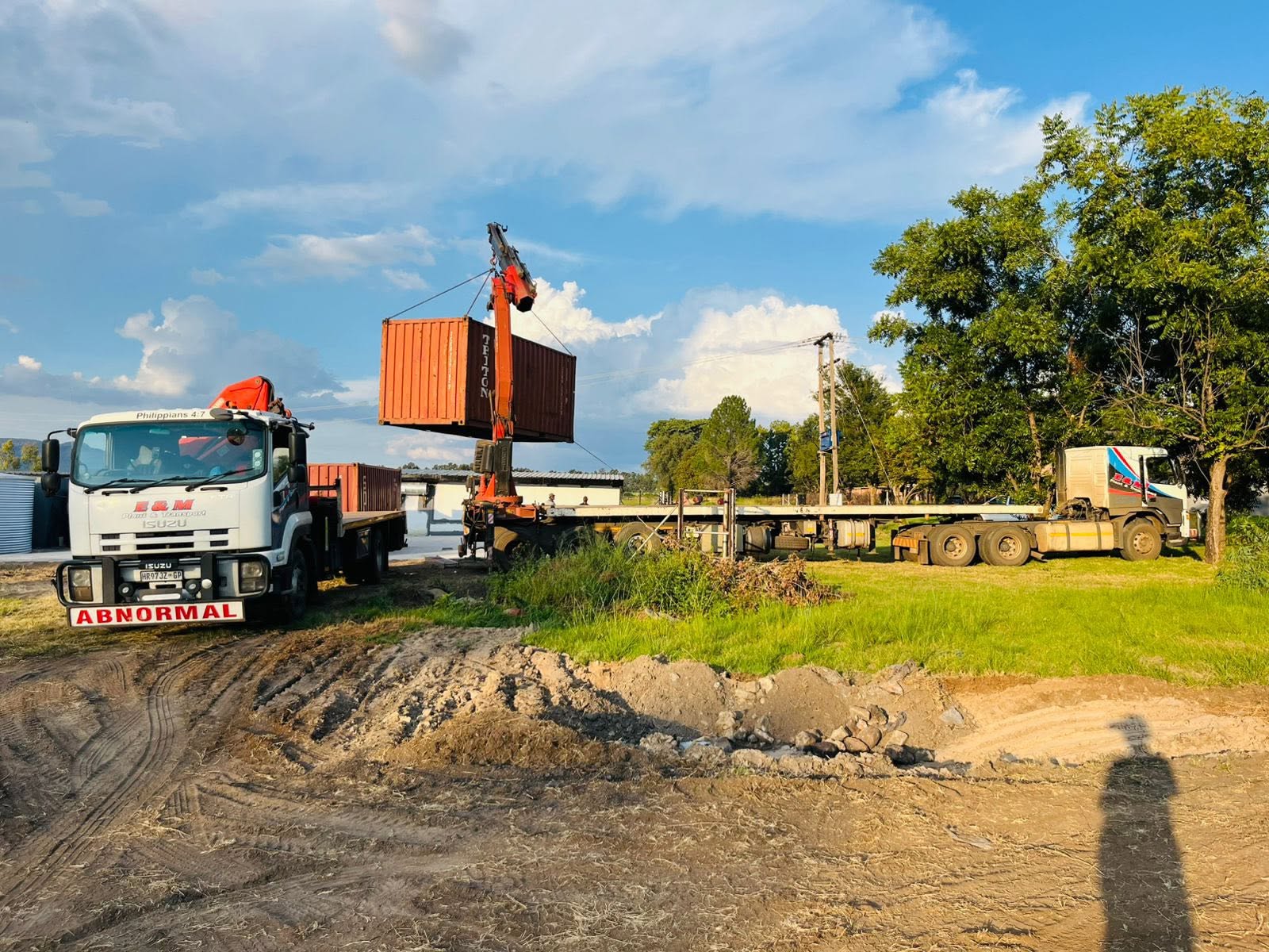 Crane truck loading a shipping container onto a lowbed